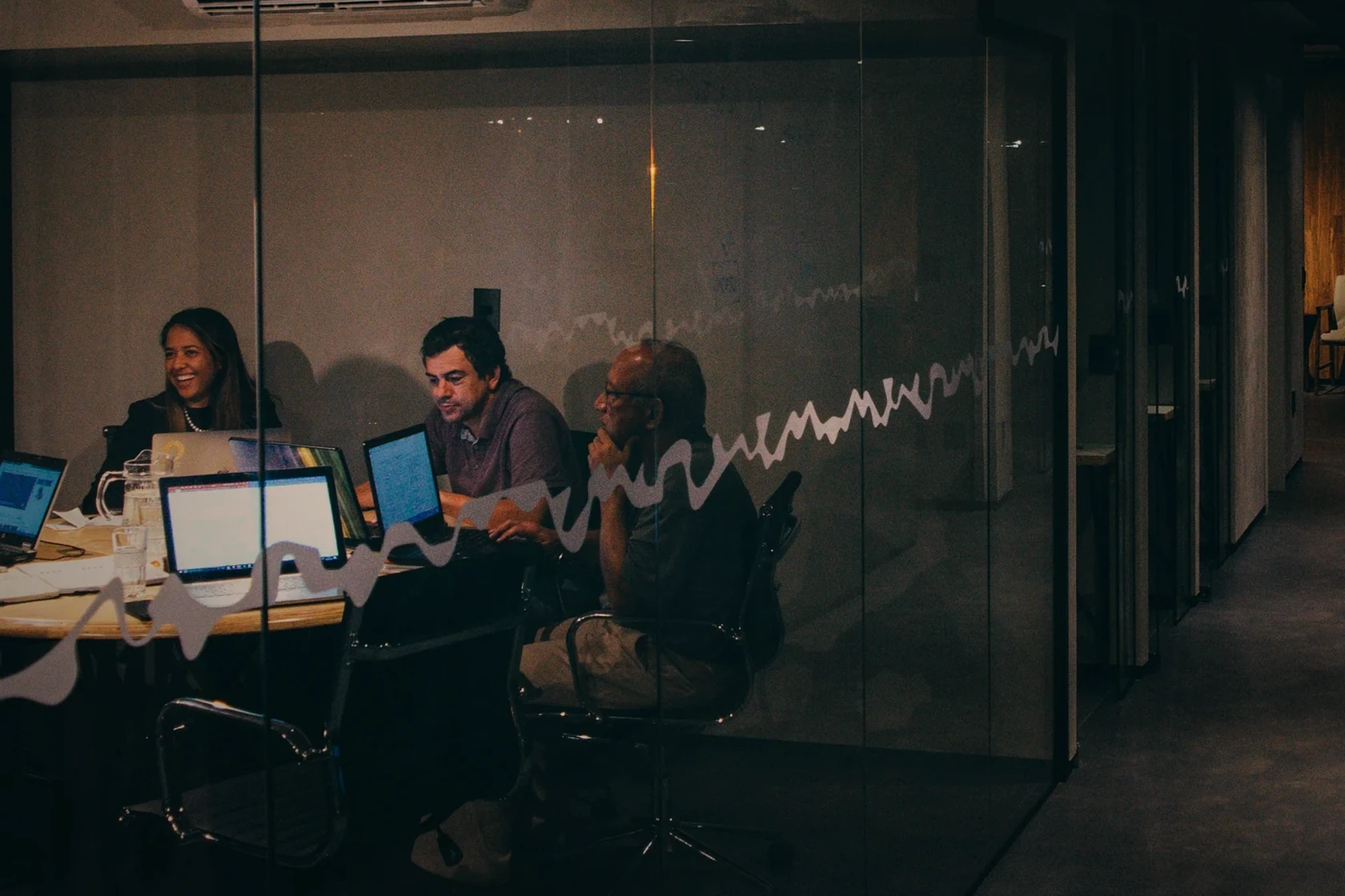 An embedded technology and business team working together inside a glass-walled office